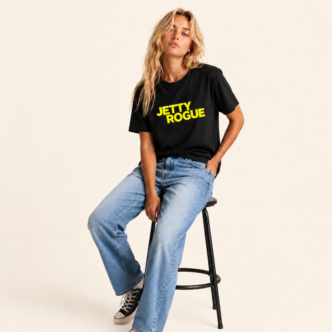  Black tee on model (seated on stool): Jetty Rogue womens tee in black with lime logo, relaxed fit, female model seated on stool