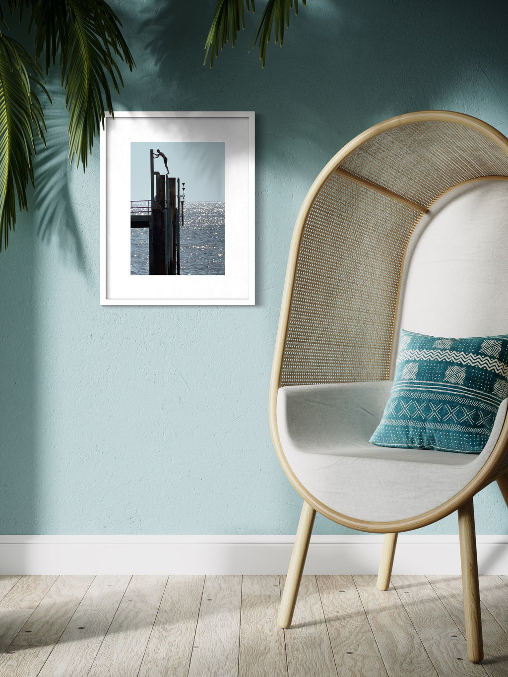 Modern interior with a wicker chair, blue cushion, and framed picture on a light blue wall.