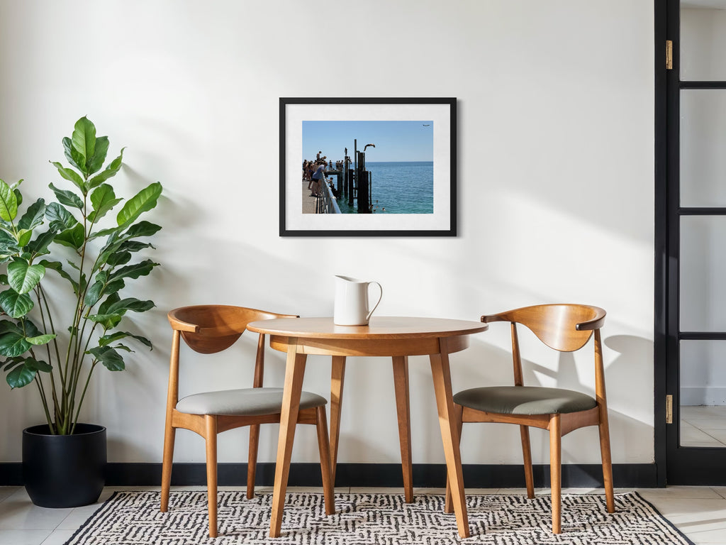 Dining area with wooden table and chairs, plant, and framed picture on wall.